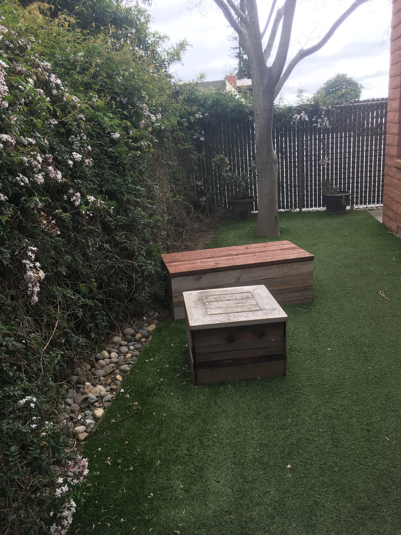 East Lake Animal Clinic's Dog Play Yard that consist of two wooden boxes to play on and sit.  Small grassy yard.