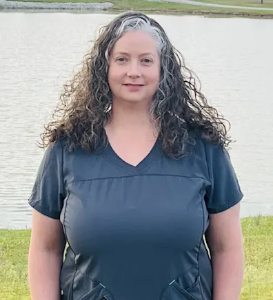 Andrea smiling standing in front of a pond