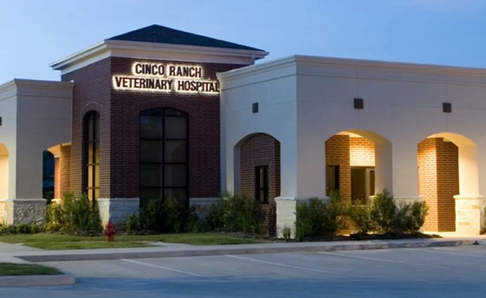 A photo of the building exterior of Cinco Ranch Veterinary Hospital at dusk