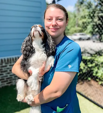 Sara Schmitz smiling hugging a brown dog outside Sara Schmitz smiling hugging a brown dog outside