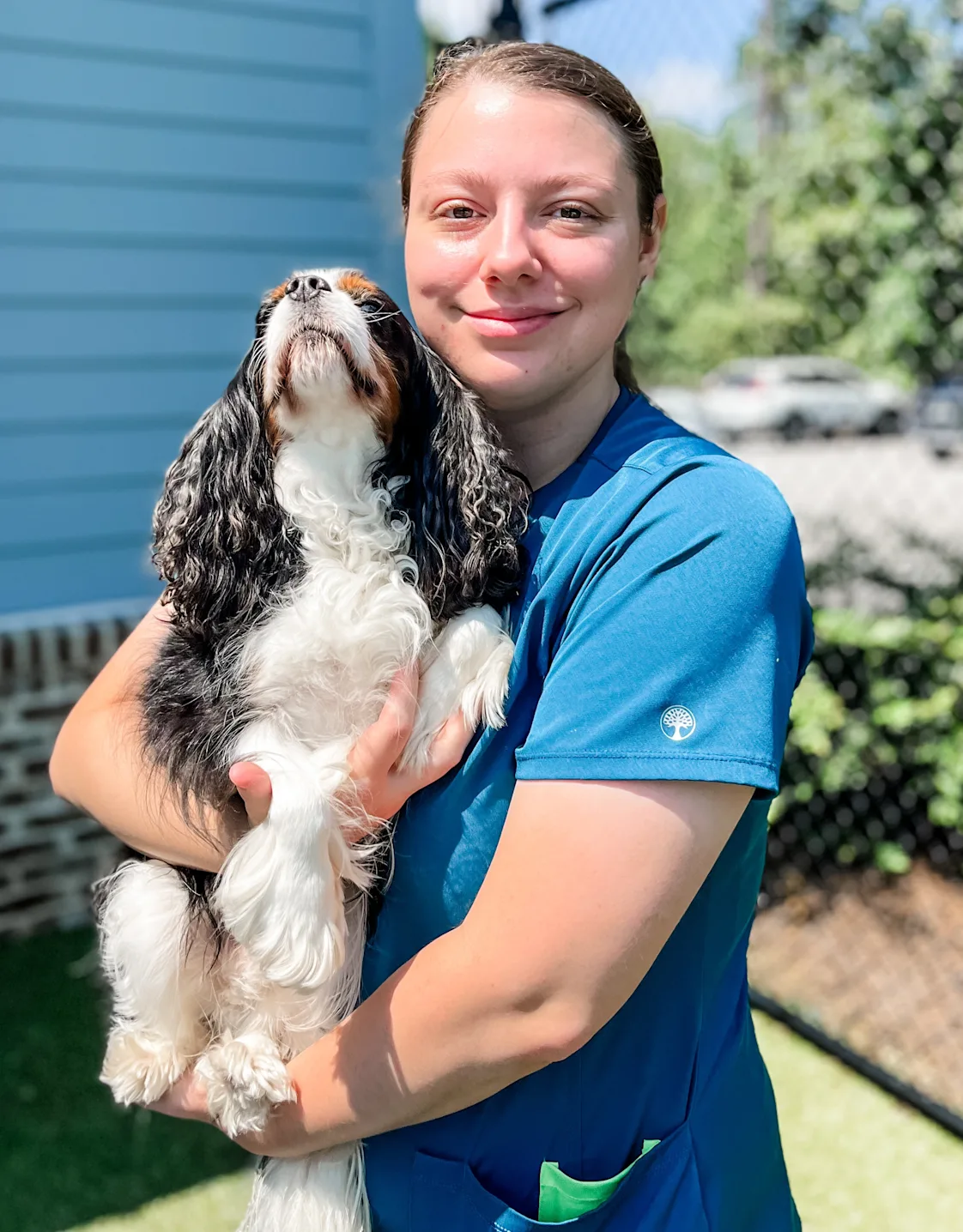 Sara Schmitz smiling hugging a brown dog outside Sara Schmitz smiling hugging a brown dog outside