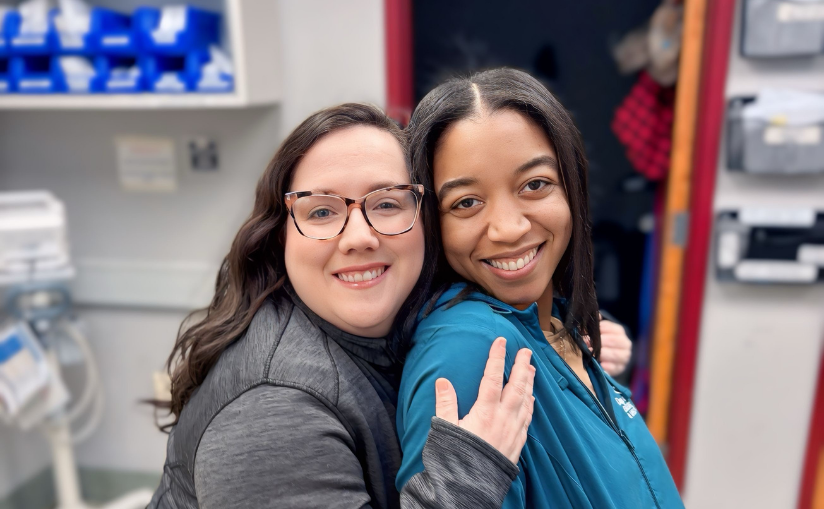 Two staff members smiling and hugging