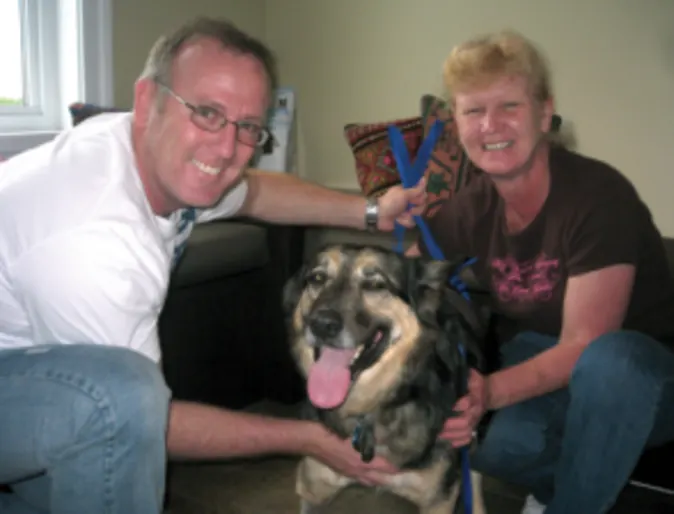 Two people smiling next to Prinz, a German Shepherd mix Two people smiling next to Prinz, a German Shepherd mix