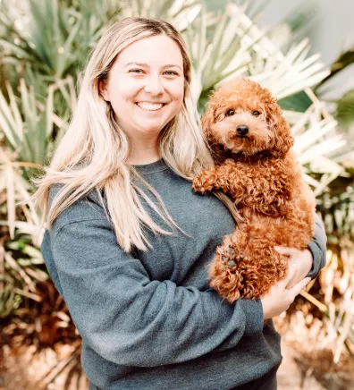 A staff member posing with a brown dog 