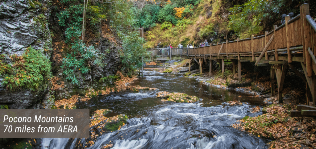 An image of the Pocono Mountains with text stating "Pocono Mountains 70 miles from AERA".