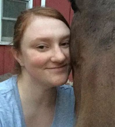 Kaycee leaned up against a brown horse's face Kaycee leaned up against a brown horse's face