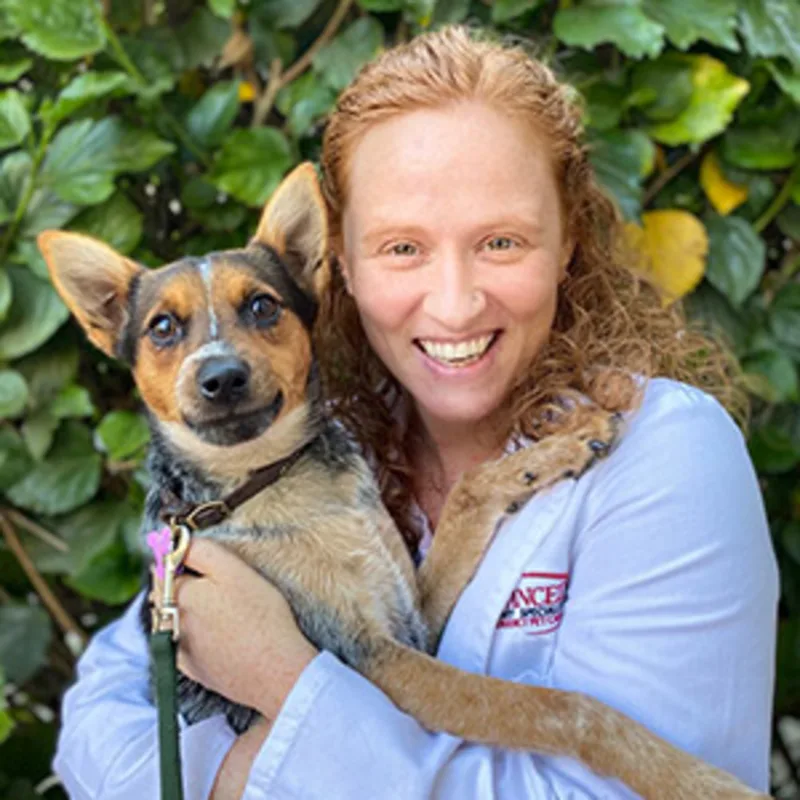 Nanelle Barash smiling holding a brown dog Nanelle Barash smiling holding a brown dog