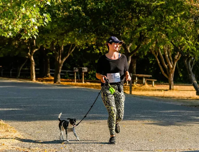 A photo of a woman walking her dog for canine fitness month A photo of a woman walking her dog for canine fitness month