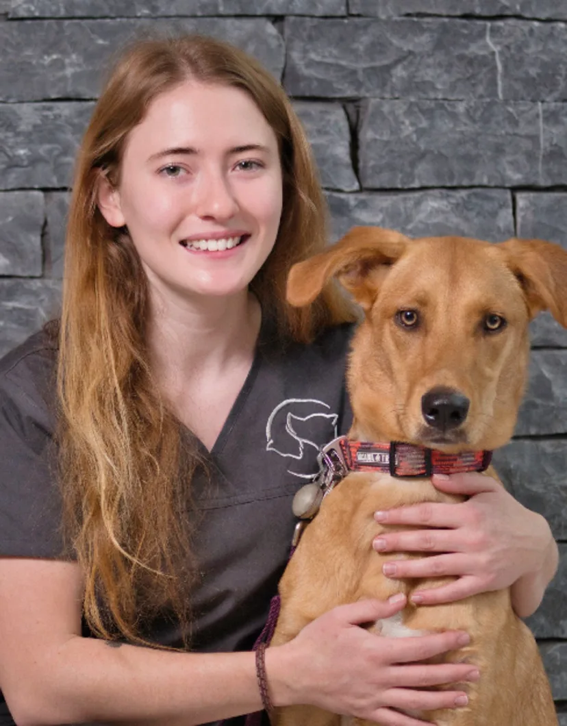 A portrait photo of Justine with a brown dog looking directly at the camera