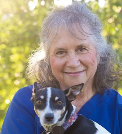 Dale smiling with a black and white dog in front of her. Dale smiling with a black and white dog in front of her.