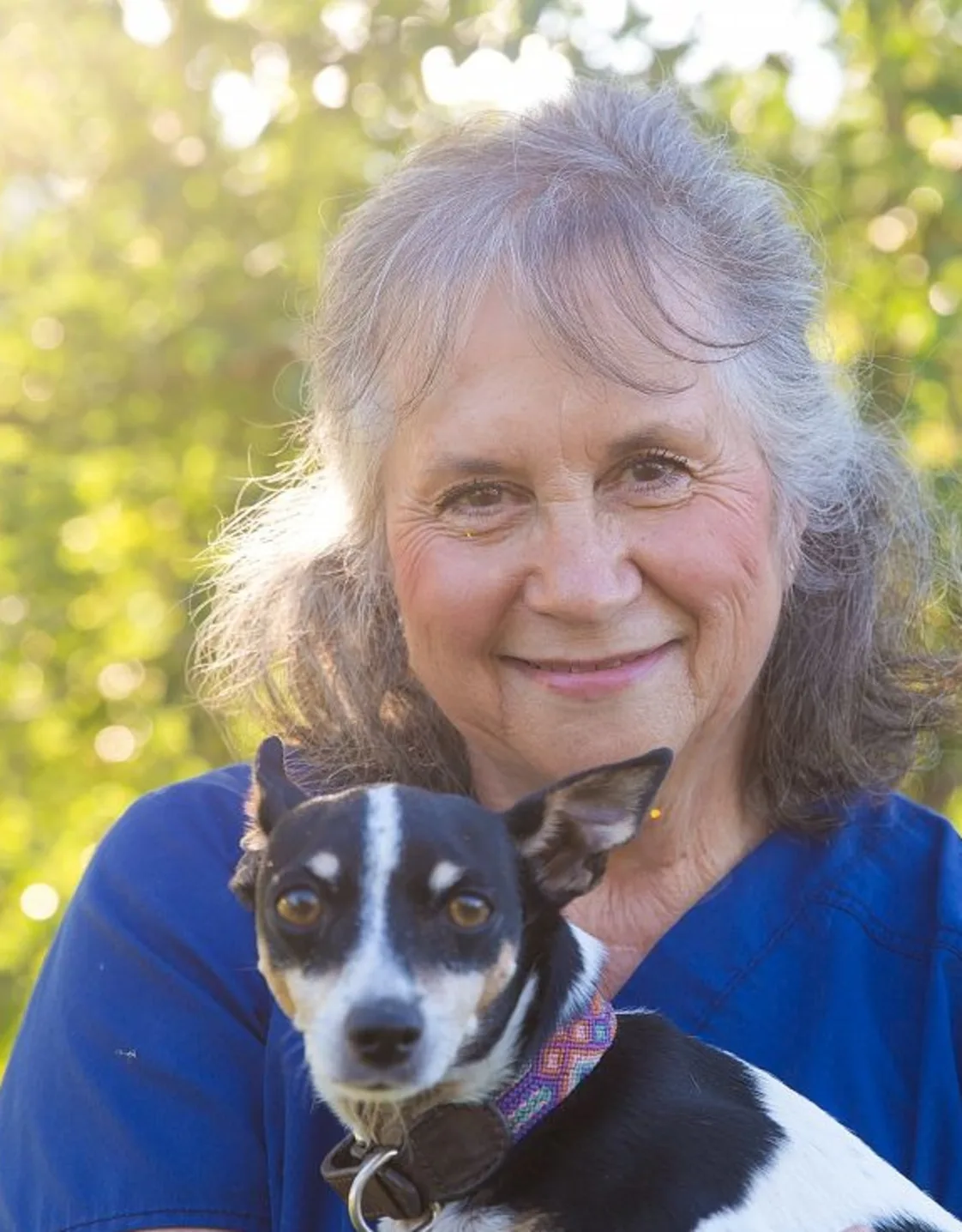 Dale smiling with a black and white dog in front of her. Dale smiling with a black and white dog in front of her.