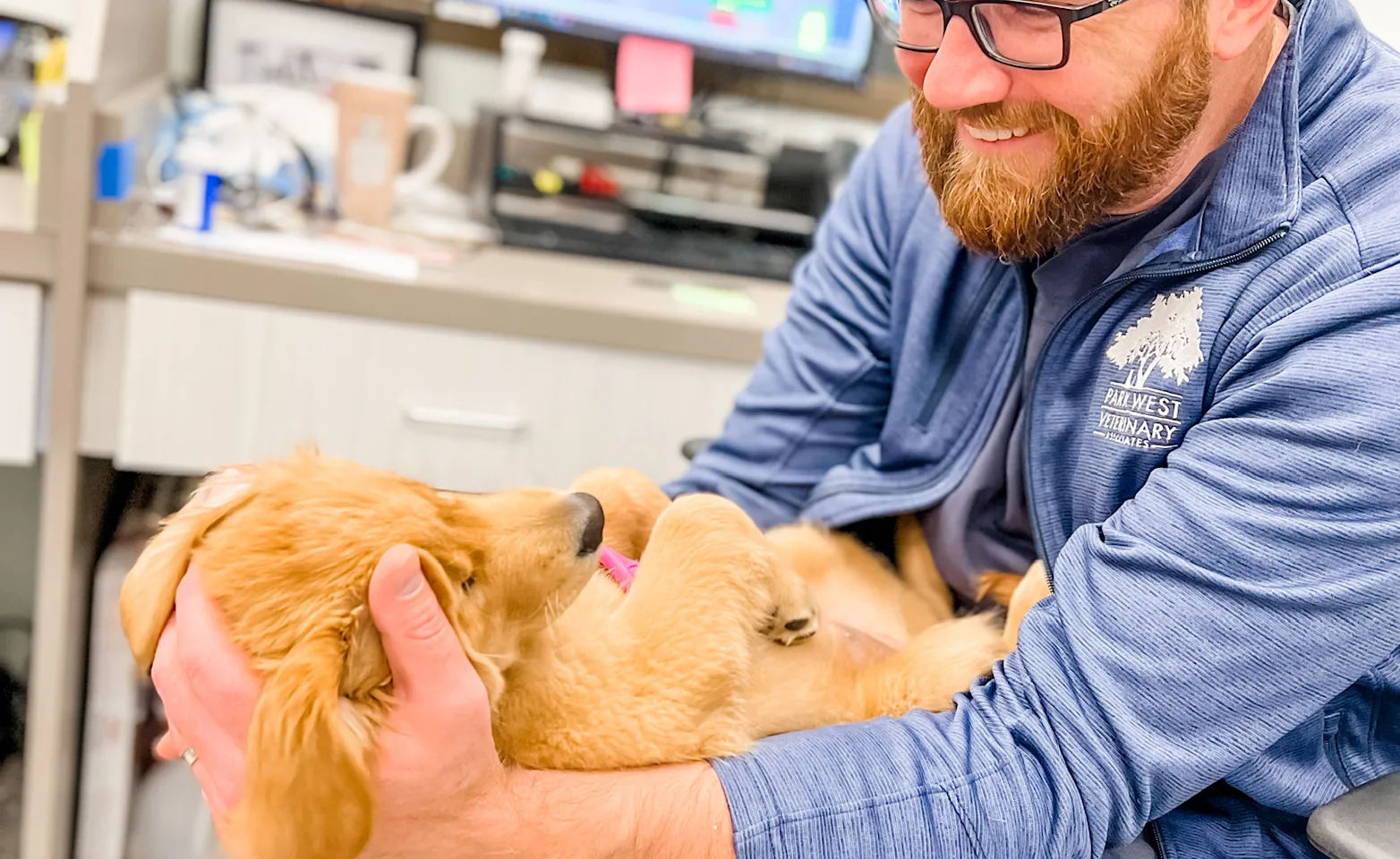 Park West Veterinary Associates staff holding a dog in lap and smiling Park West Veterinary Associates staff holding a dog in lap and smiling