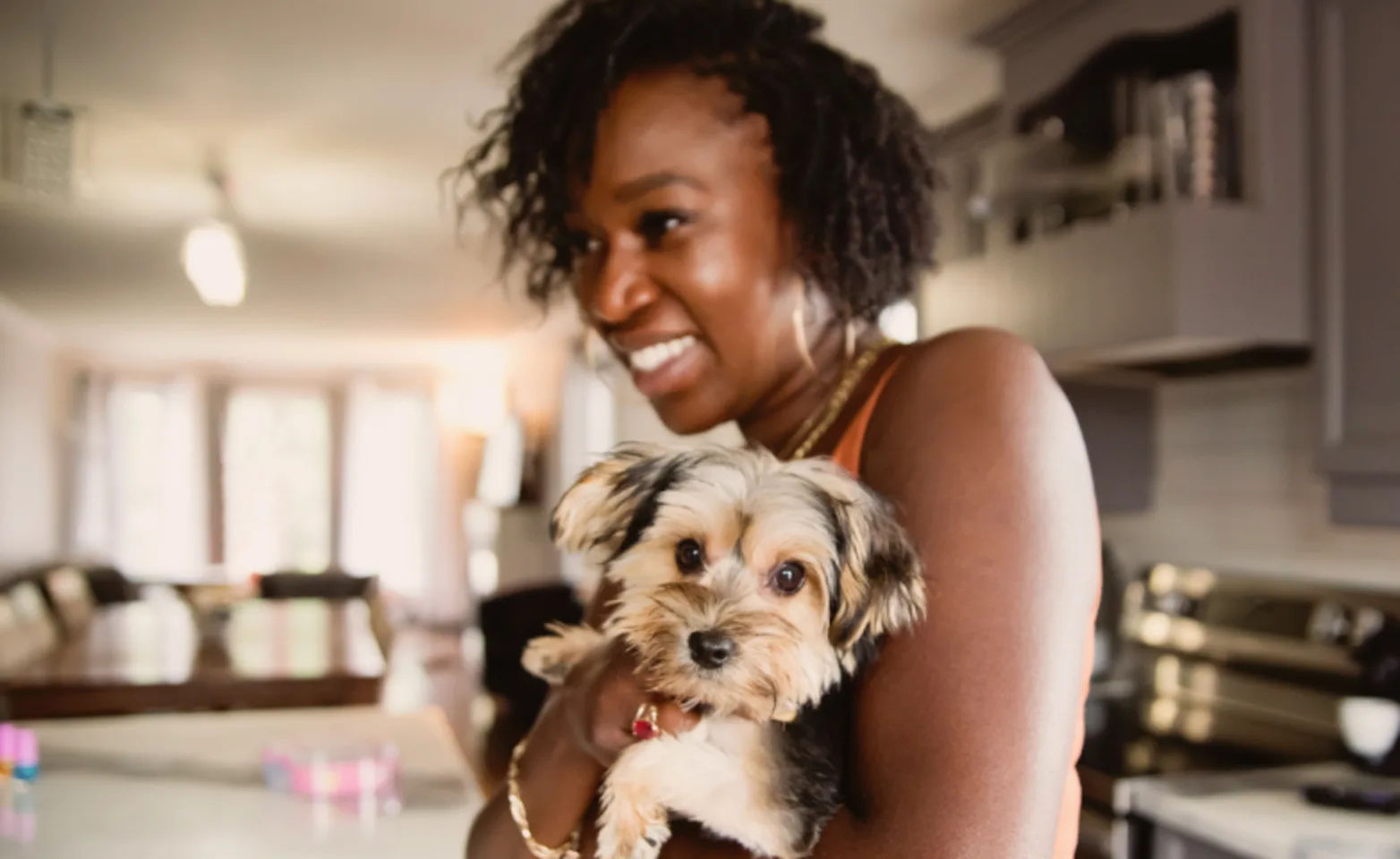 Woman holding a small dog in her home Woman holding a small dog in her home
