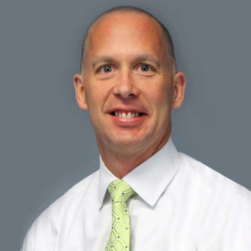 Matthew Pearson smiling in front of a grey wall Matthew Pearson smiling in front of a grey wall