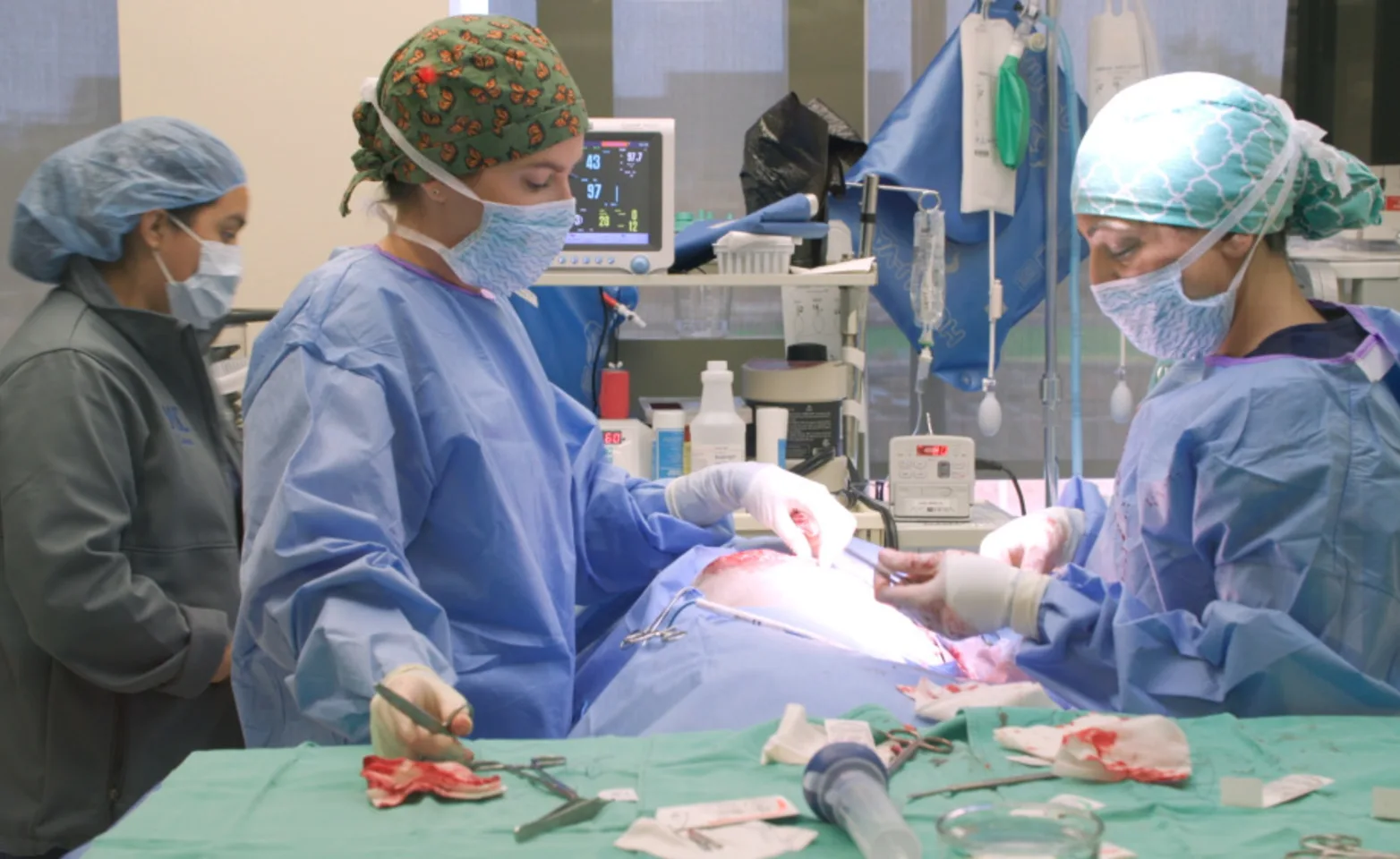 Three staff members dresses in surgical gear performing surgery