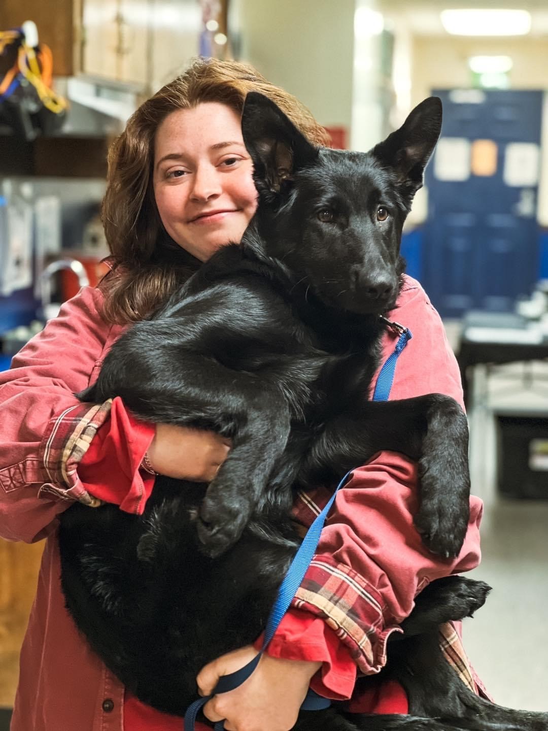 Staff member holding a black dog