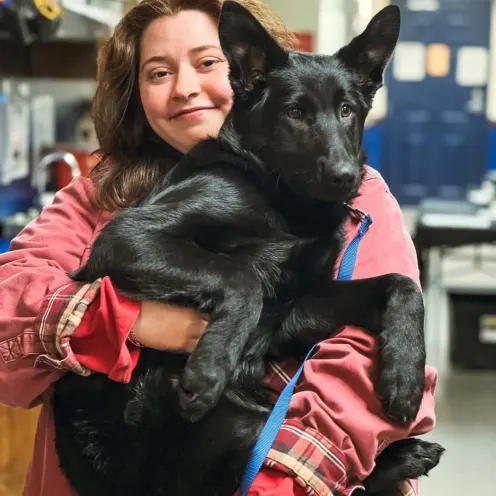 Staff member holding a black dog