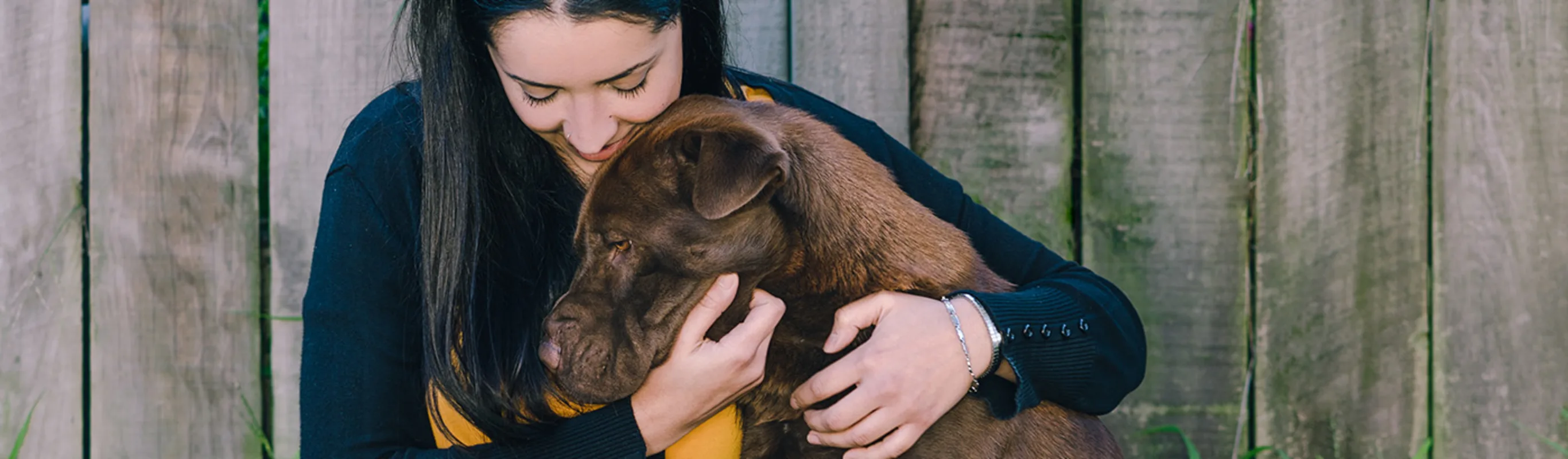 Woman hugs dog against fence Woman hugs dog against fence