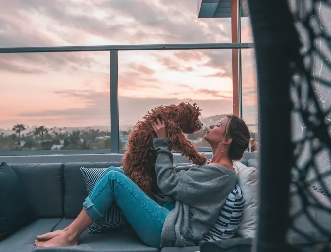 woman holding dog on a balcony couch