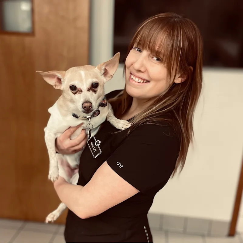Nikki smiling, holding a light brown dog Nikki smiling, holding a light brown dog