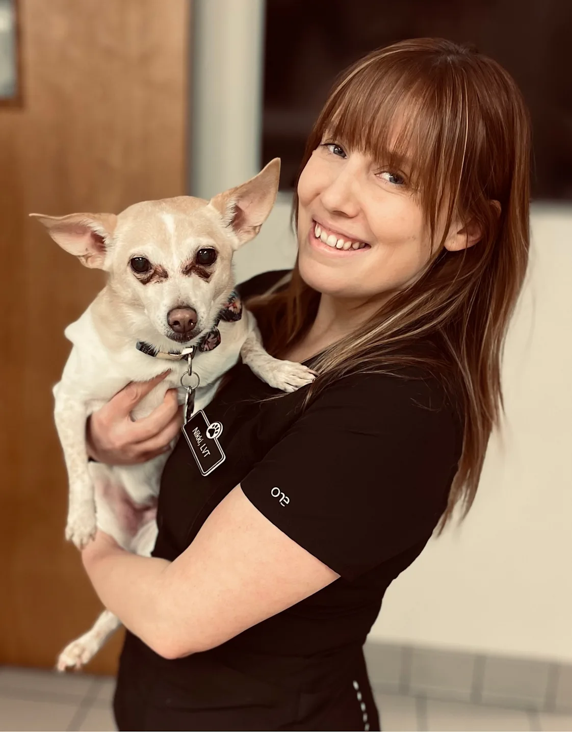 Nikki smiling, holding a light brown dog Nikki smiling, holding a light brown dog