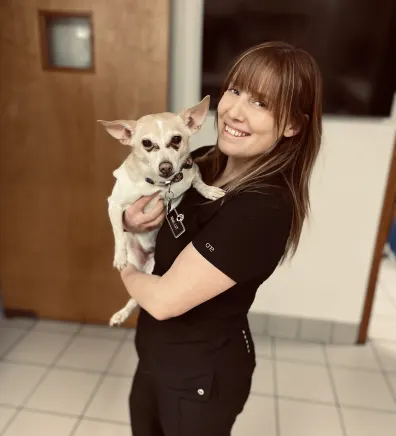 Nikki smiling, holding a light brown dog