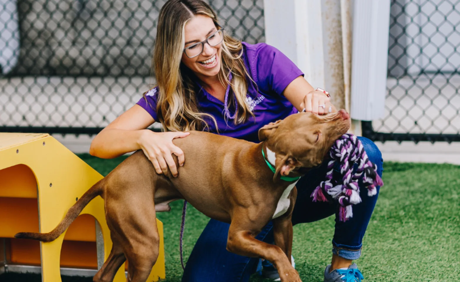 A PetSuites staff member plays with a dog. A PetSuites staff member plays with a dog.