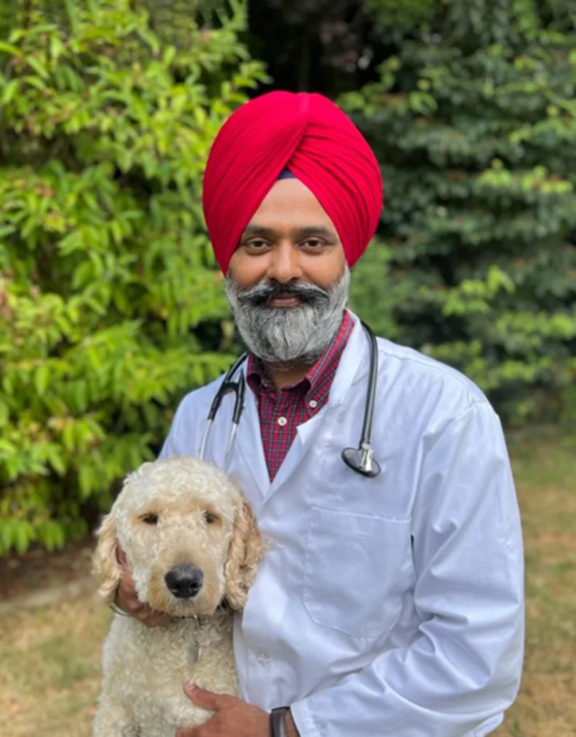 Dr. Mundi holding his small blond dog, Raavi, with trees in the background