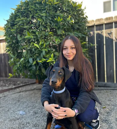 A staff member posing with black dog A staff member posing with black dog
