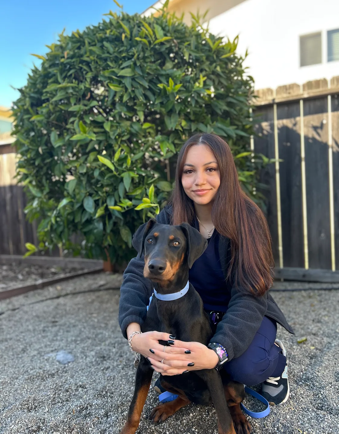 A staff member posing with black dog A staff member posing with black dog