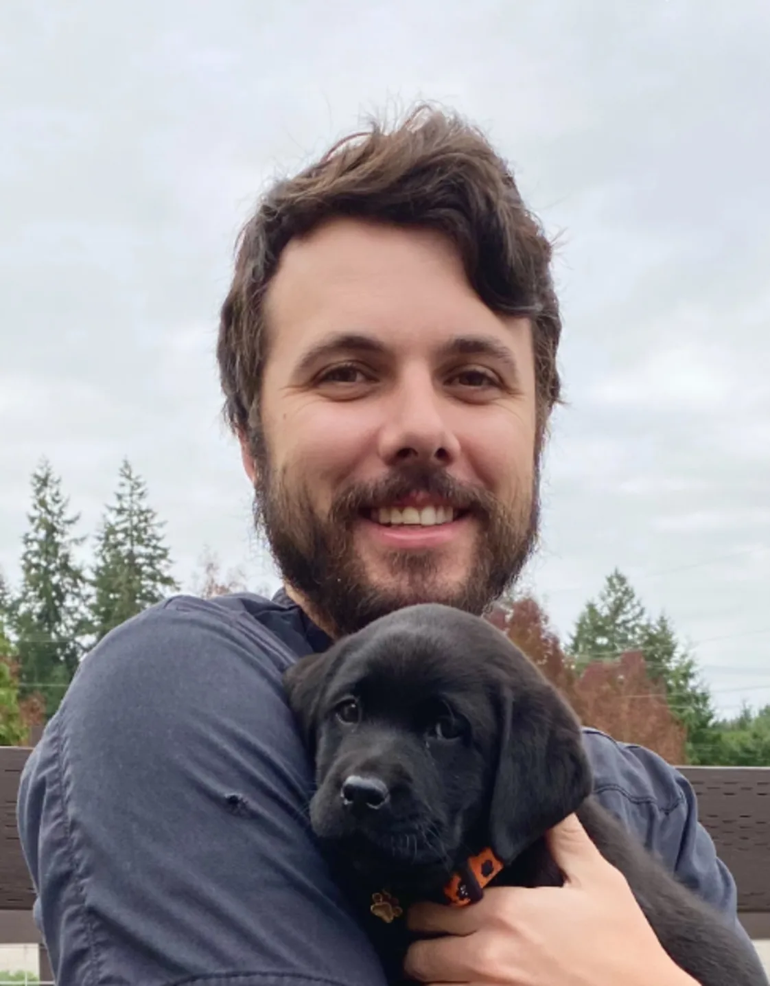 Dr. Ethan Walsh holding a little black puppy Dr. Ethan Walsh holding a little black puppy