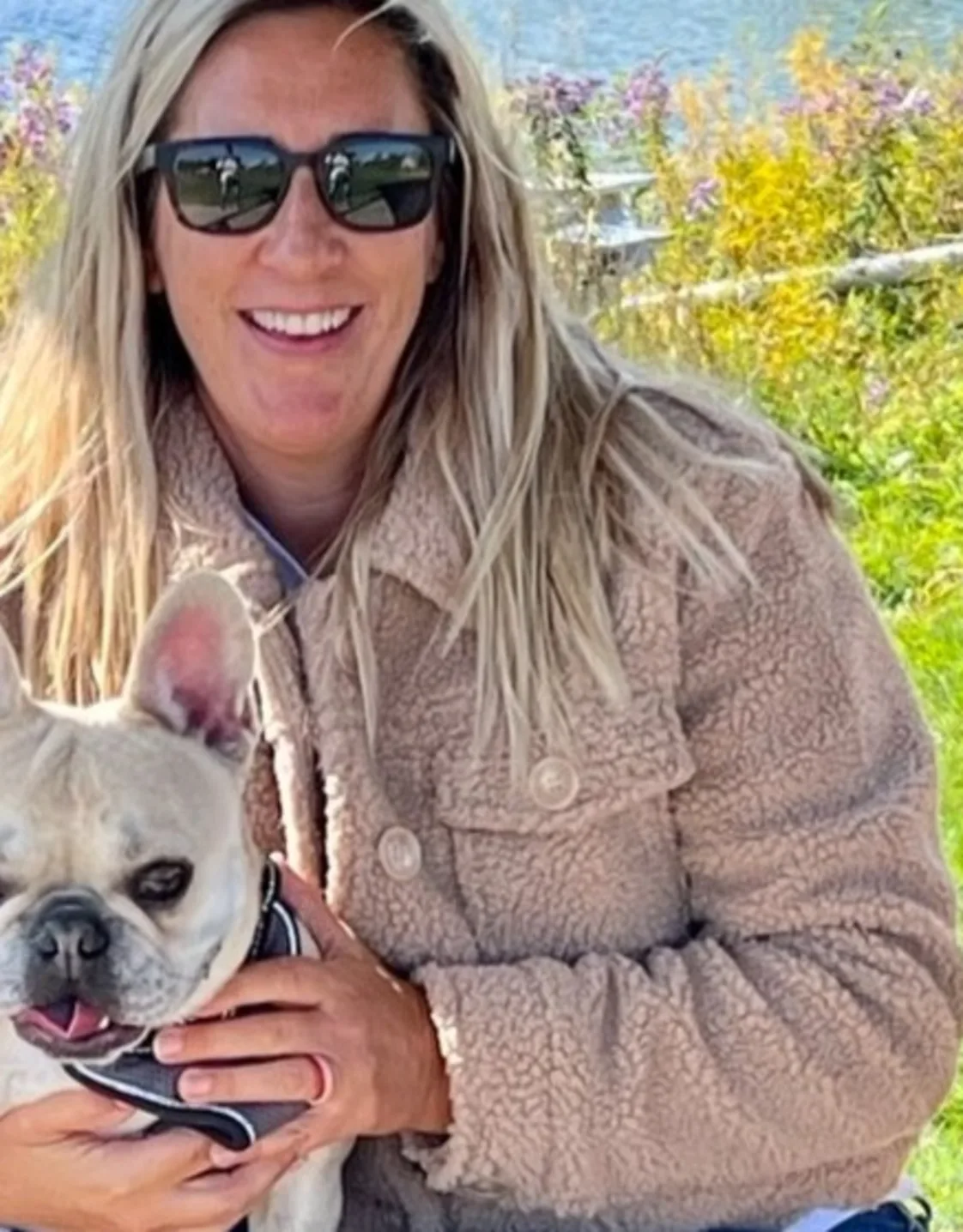 Eve smiling in front of a lake holding a small white dog Eve smiling in front of a lake holding a small white dog