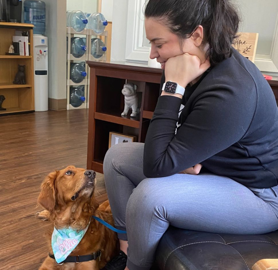 Lady sitting and looking at golden dog laying on the floor