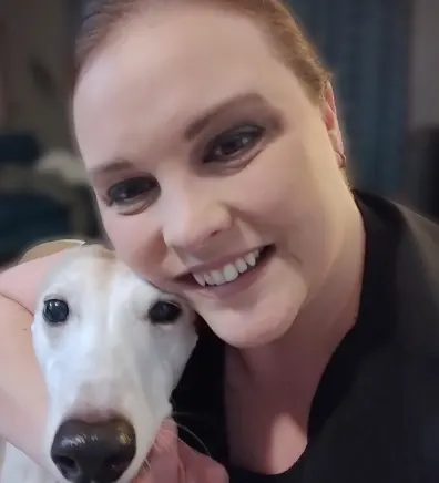 Jennifer smiling, hugging a large white dog
