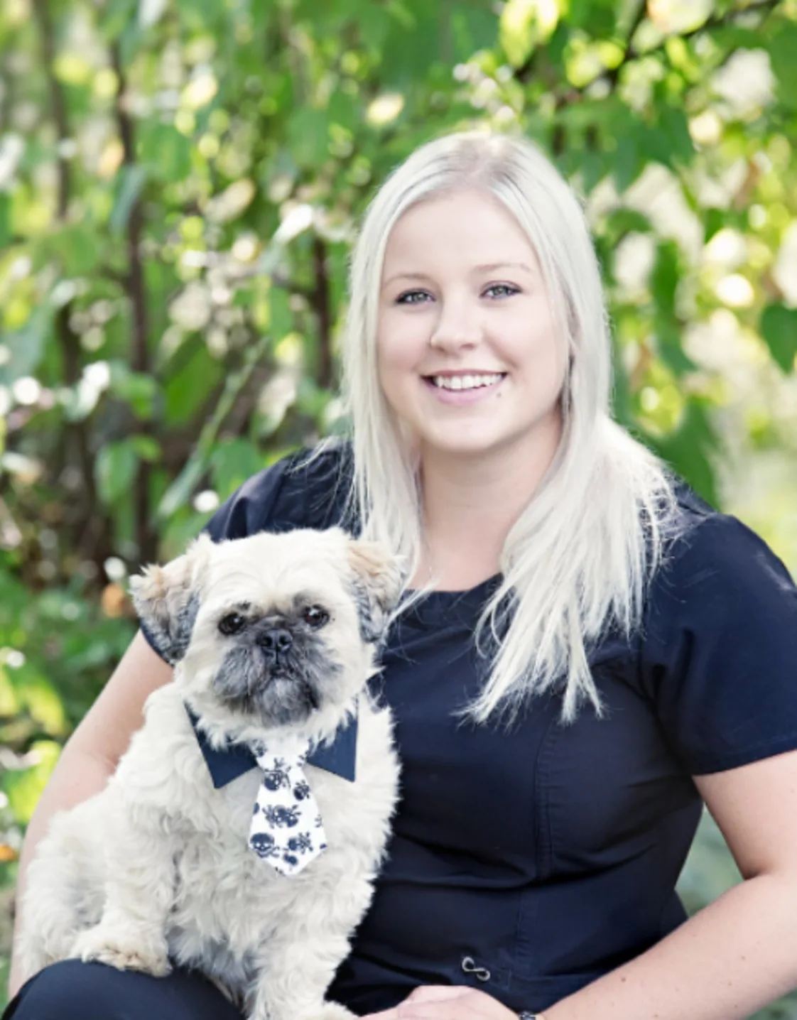 Nicole holding a little white dog with a tie on Nicole holding a little white dog with a tie on