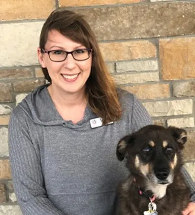 Lisa kneeling down in front of a brick wall next to a black and brown dog Lisa kneeling down in front of a brick wall next to a black and brown dog