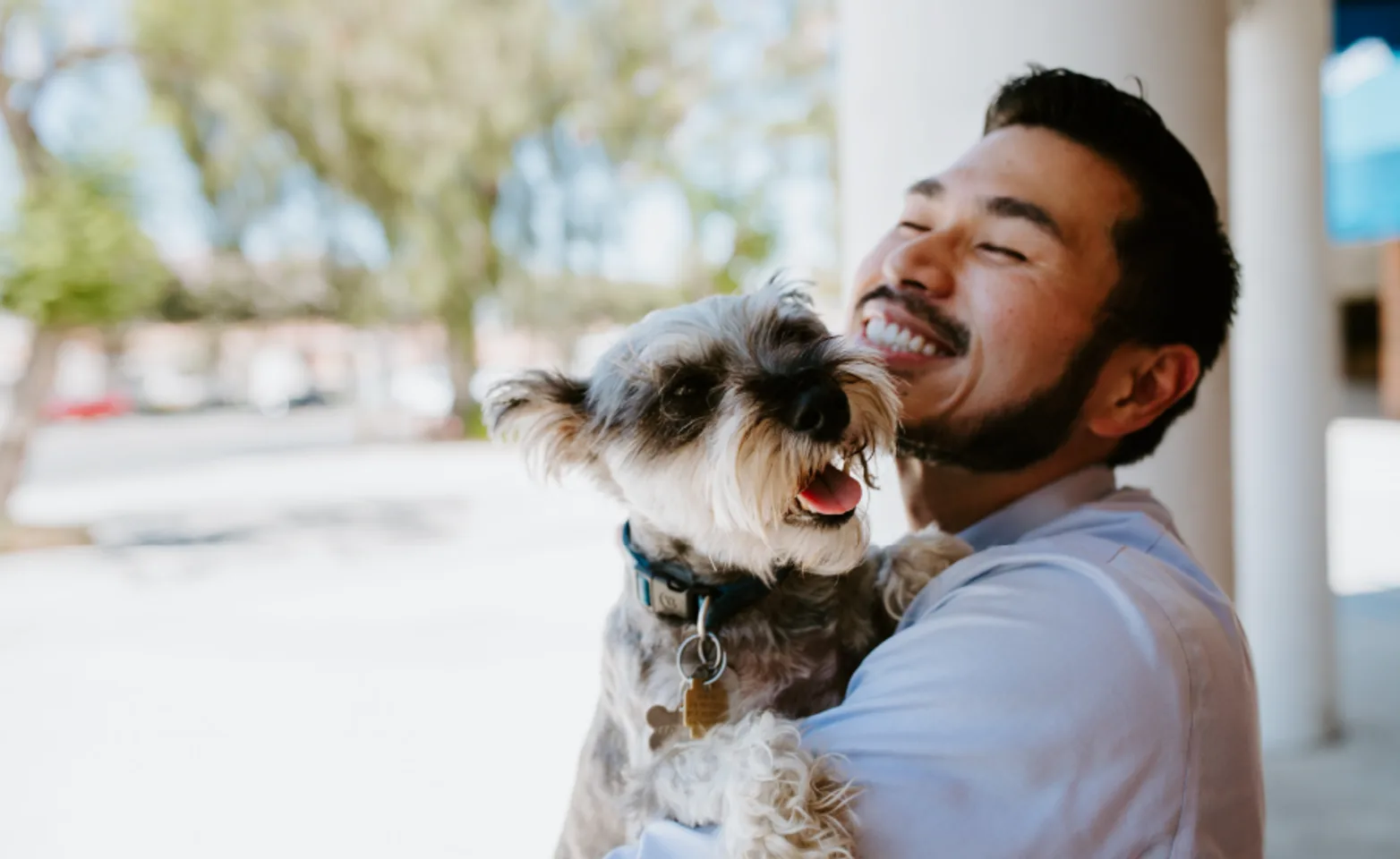 Man smiling and holding a dog outside Man smiling and holding a dog outside