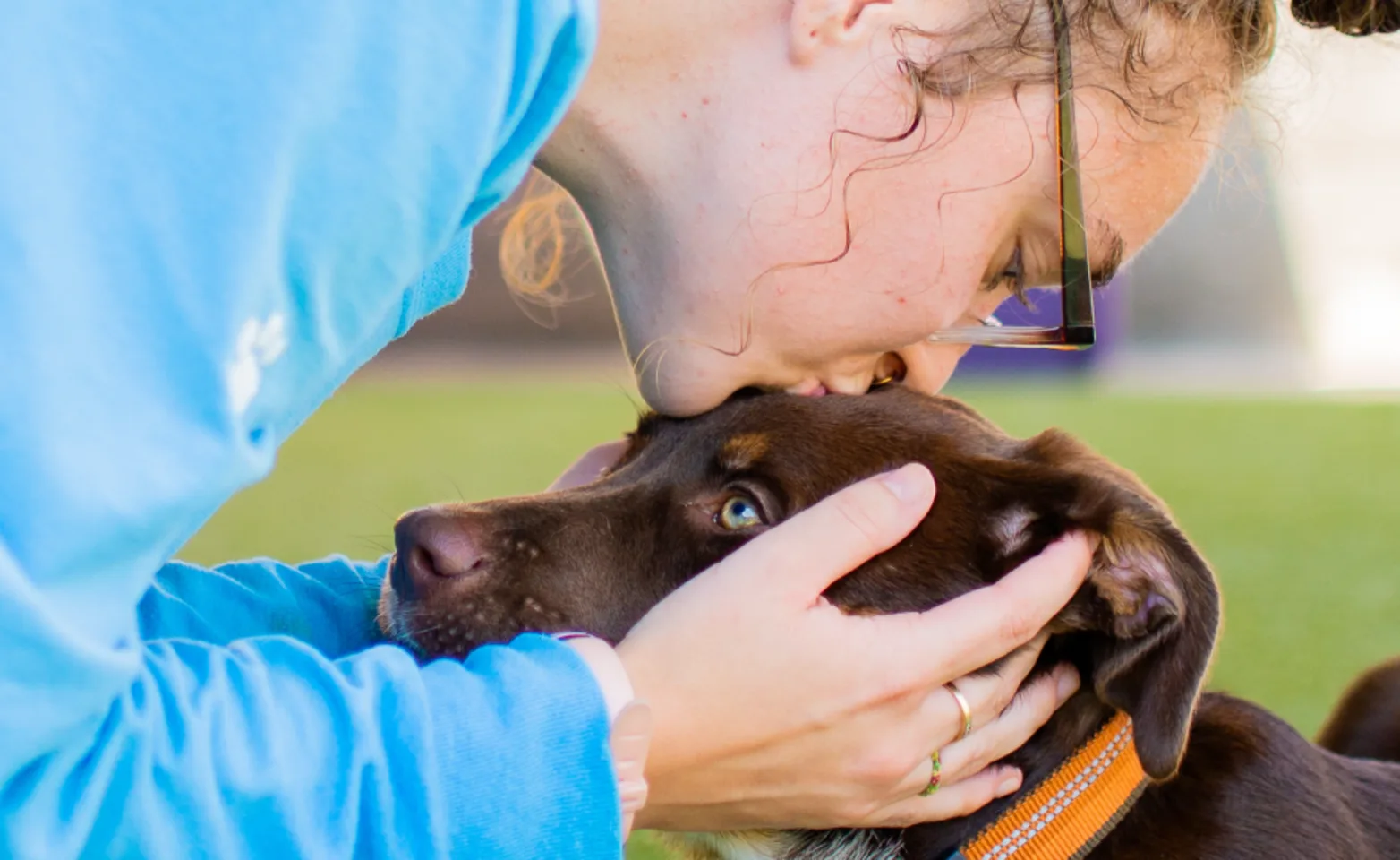 Staff member kissing dog 