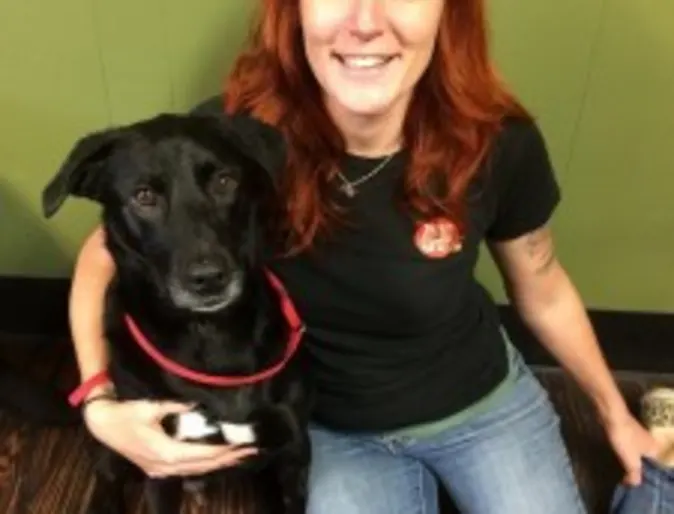 a red-haired woman sits on the floor with a black dog a red-haired woman sits on the floor with a black dog