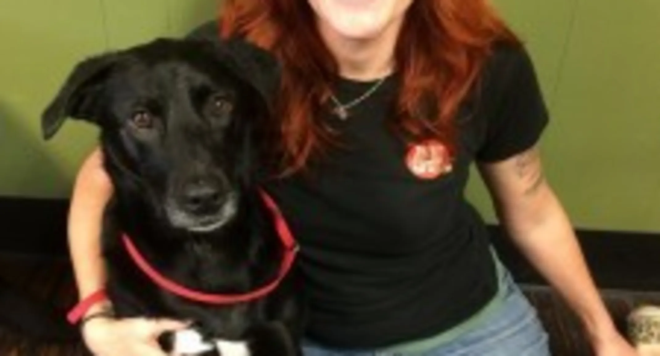 a red-haired woman sits on the floor with a black dog a red-haired woman sits on the floor with a black dog