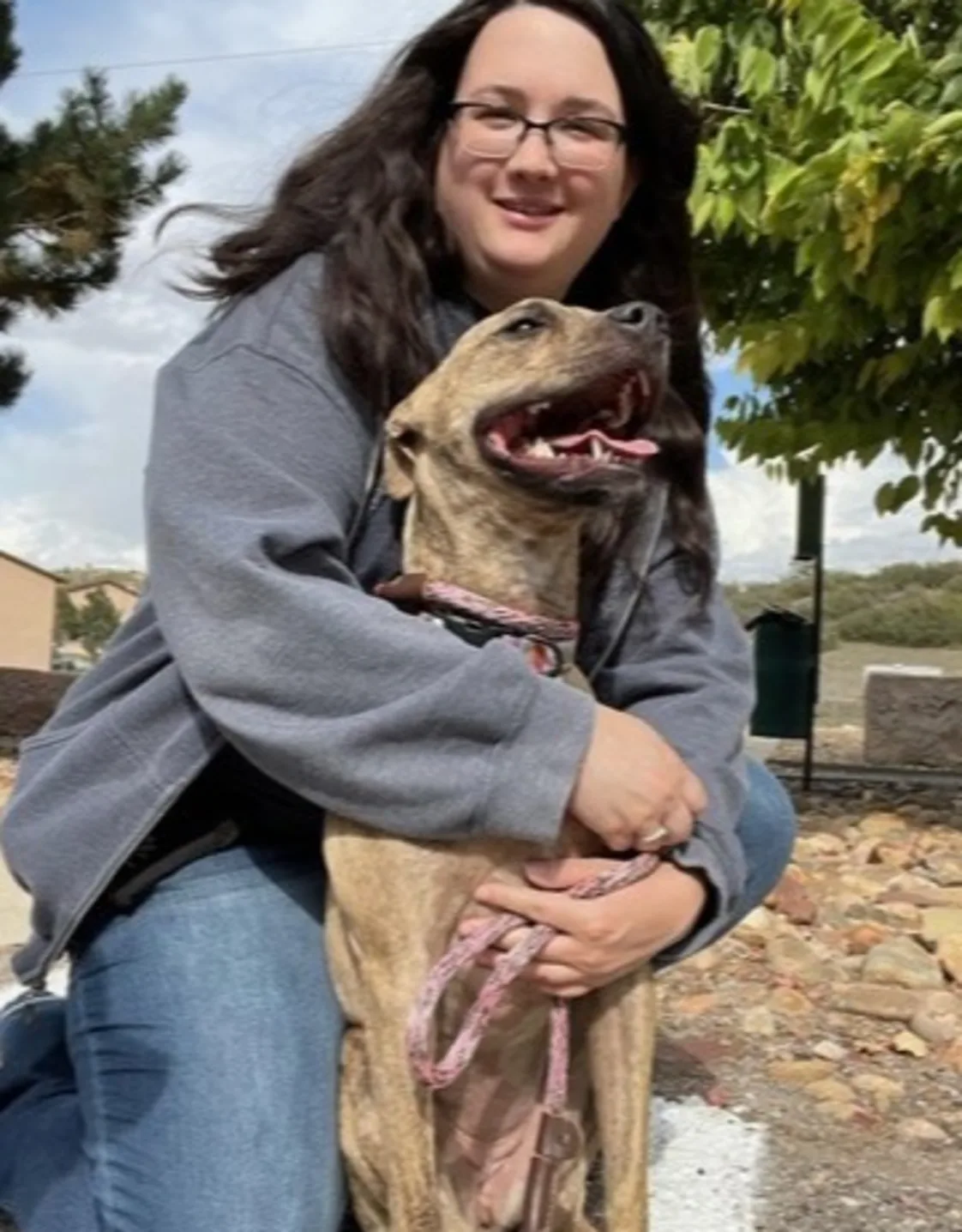 Samantha posing outdoors and holding a large brown dog Samantha posing outdoors and holding a large brown dog