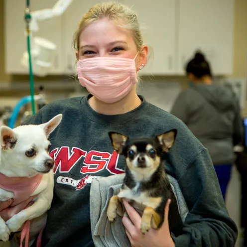 Woman holding two dogs.