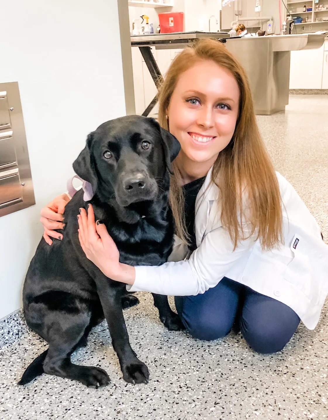 Dr. Tara Harasim smiling kneeling down next to a Black Lab Dr. Tara Harasim smiling kneeling down next to a Black Lab