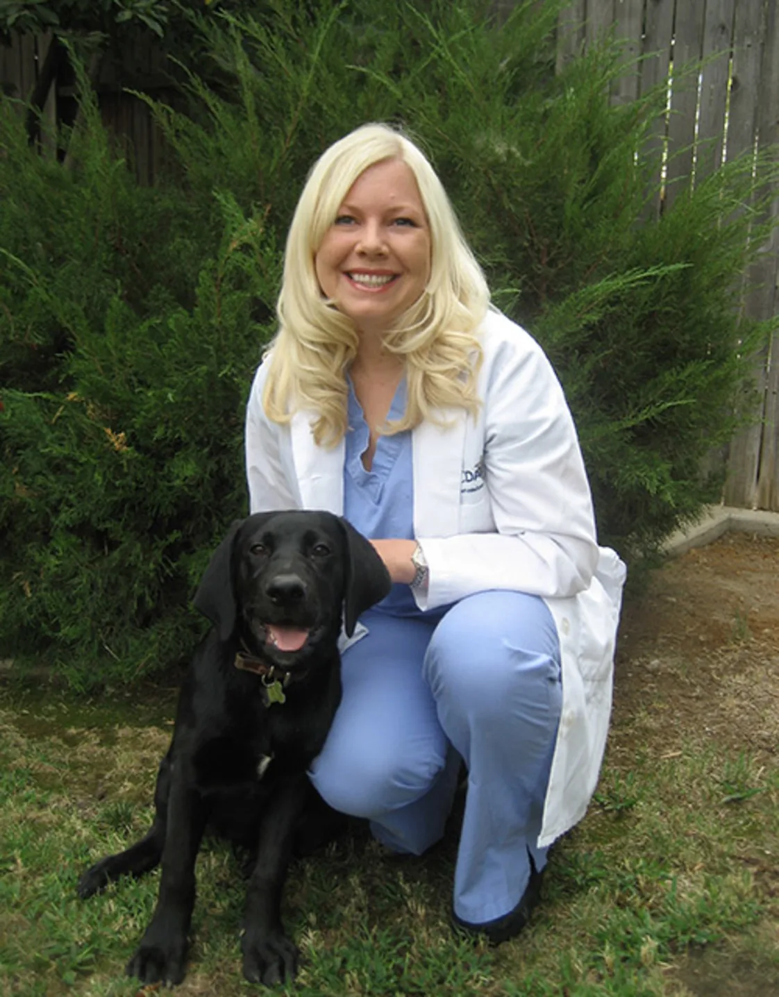 Dr. Stephanie Anne Paine crouching next to a black dog. Dr. Stephanie Anne Paine crouching next to a black dog.