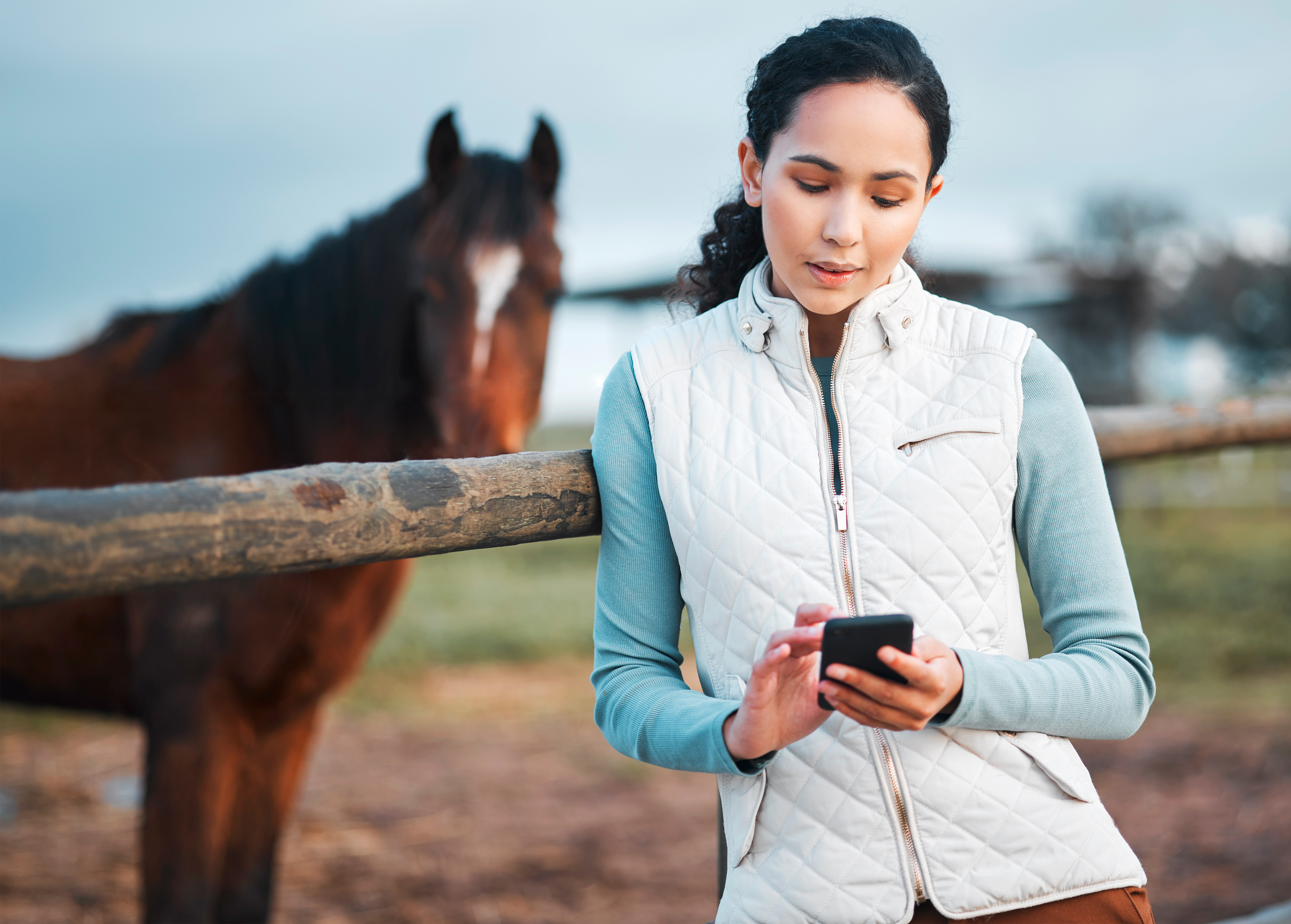 Woman on phone next to horse