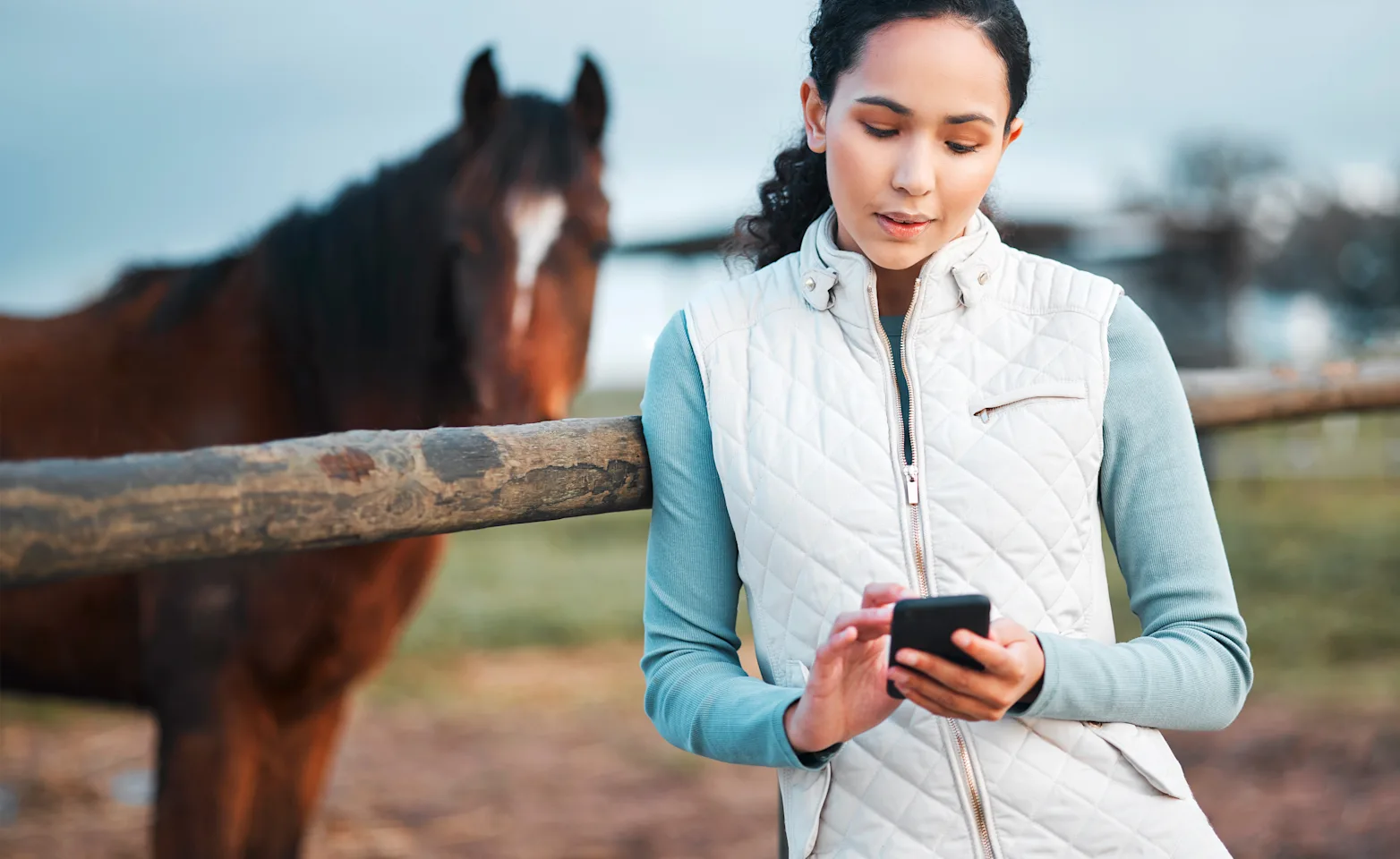Woman on phone next to horse Woman on phone next to horse