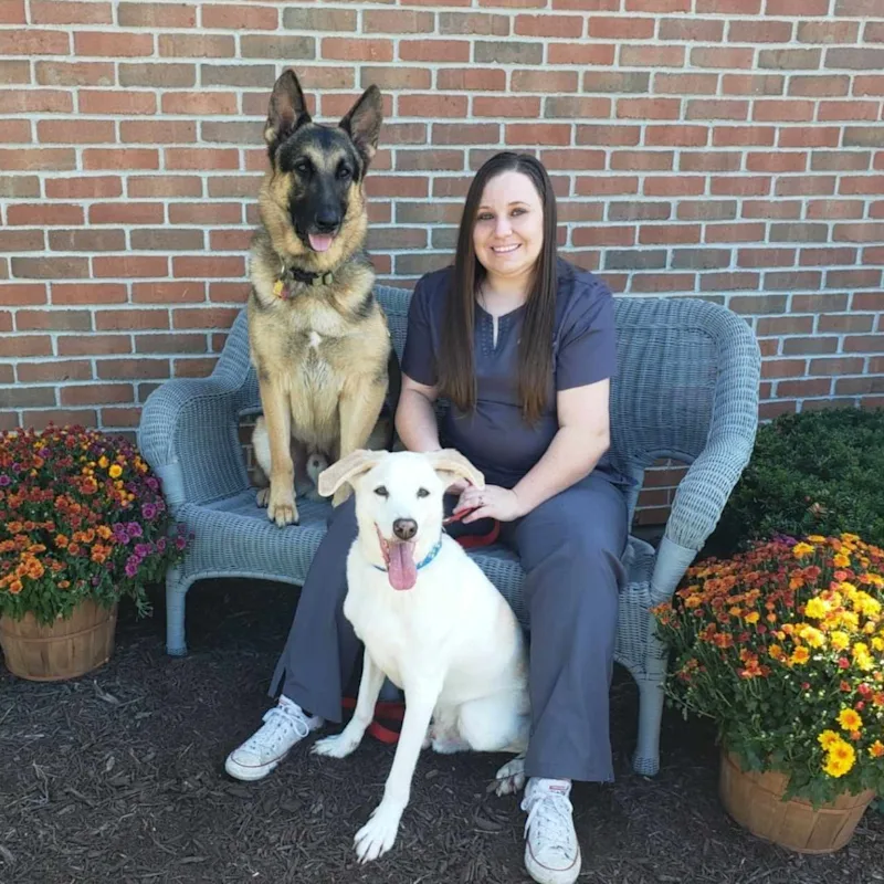 Assistant Manager Megan H posing with a German Shepherd and a white dog Assistant Manager Megan H posing with a German Shepherd and a white dog