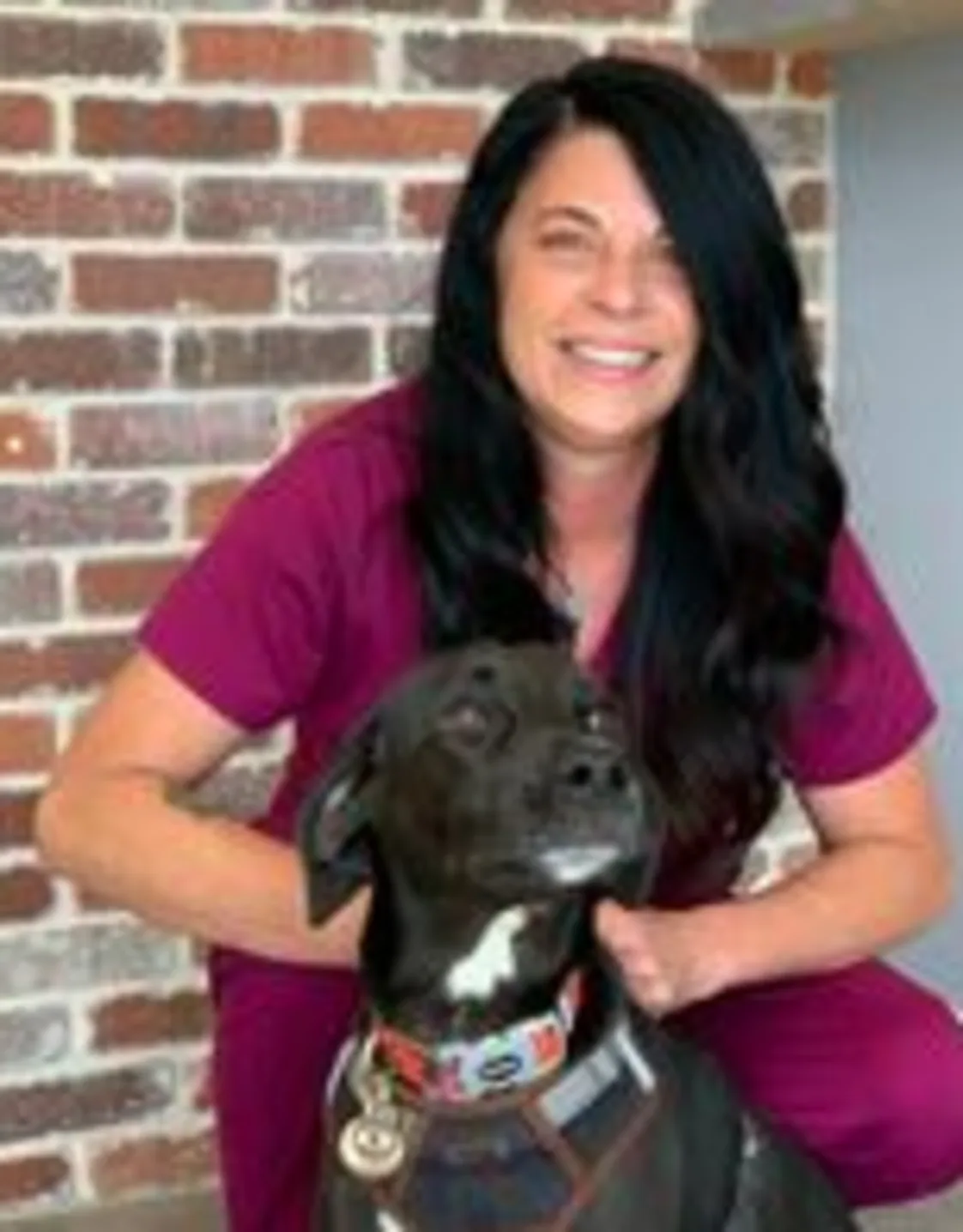 Kim Parmenter kneeling down next to a black and white dog Kim Parmenter kneeling down next to a black and white dog