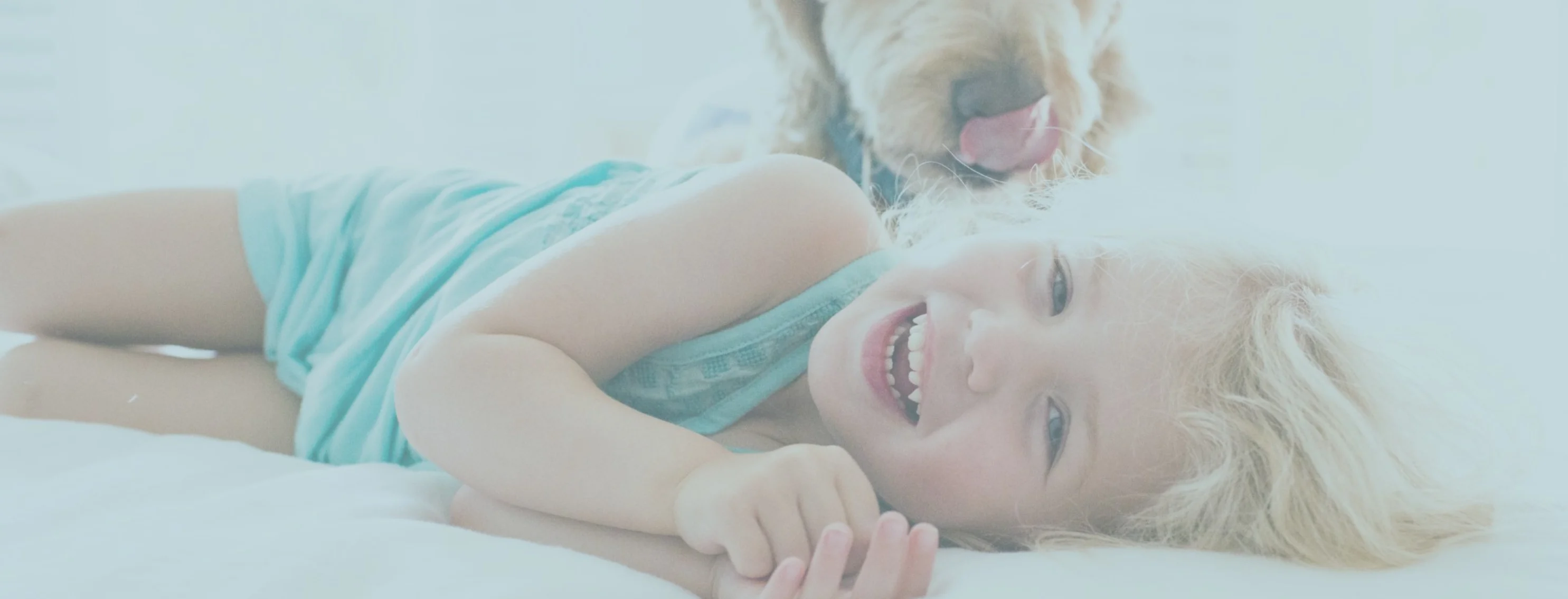 Girl lying down and smiling at the camera with a dog Girl lying down and smiling at the camera with a dog