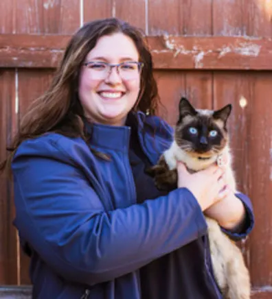 Laurynn standing in front of a wood fence holding a siamese cat Laurynn standing in front of a wood fence holding a siamese cat